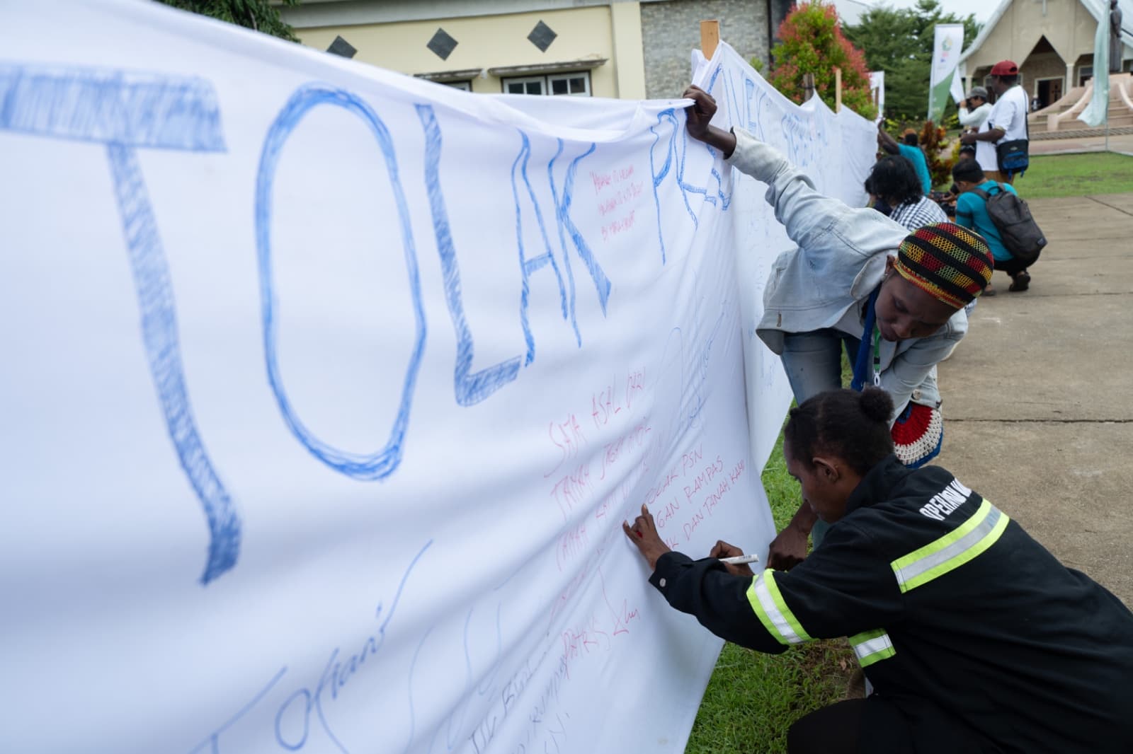 Warga terdampak PSN membubuhkan tandatangan dalam spanduk Tolak PSN dalam acara Konsolidasi Solidaritas Merauke, 11-14 Maret 2025, di Merauke. Foto: Ist.