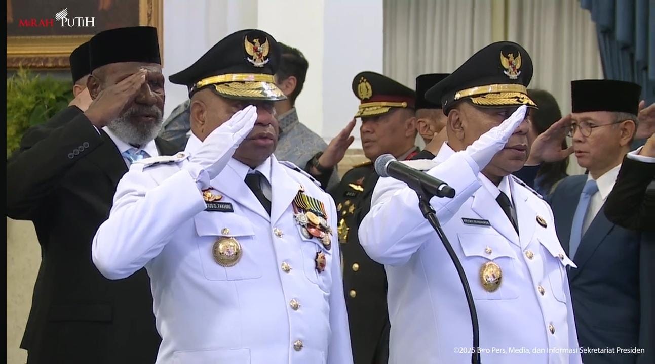 Tampak Mathius D Fakhiri dan Aryoko Rumaropen mengenakan PDU berwarna putih dengan sikap hormat. Foto : Tangkapan layar.