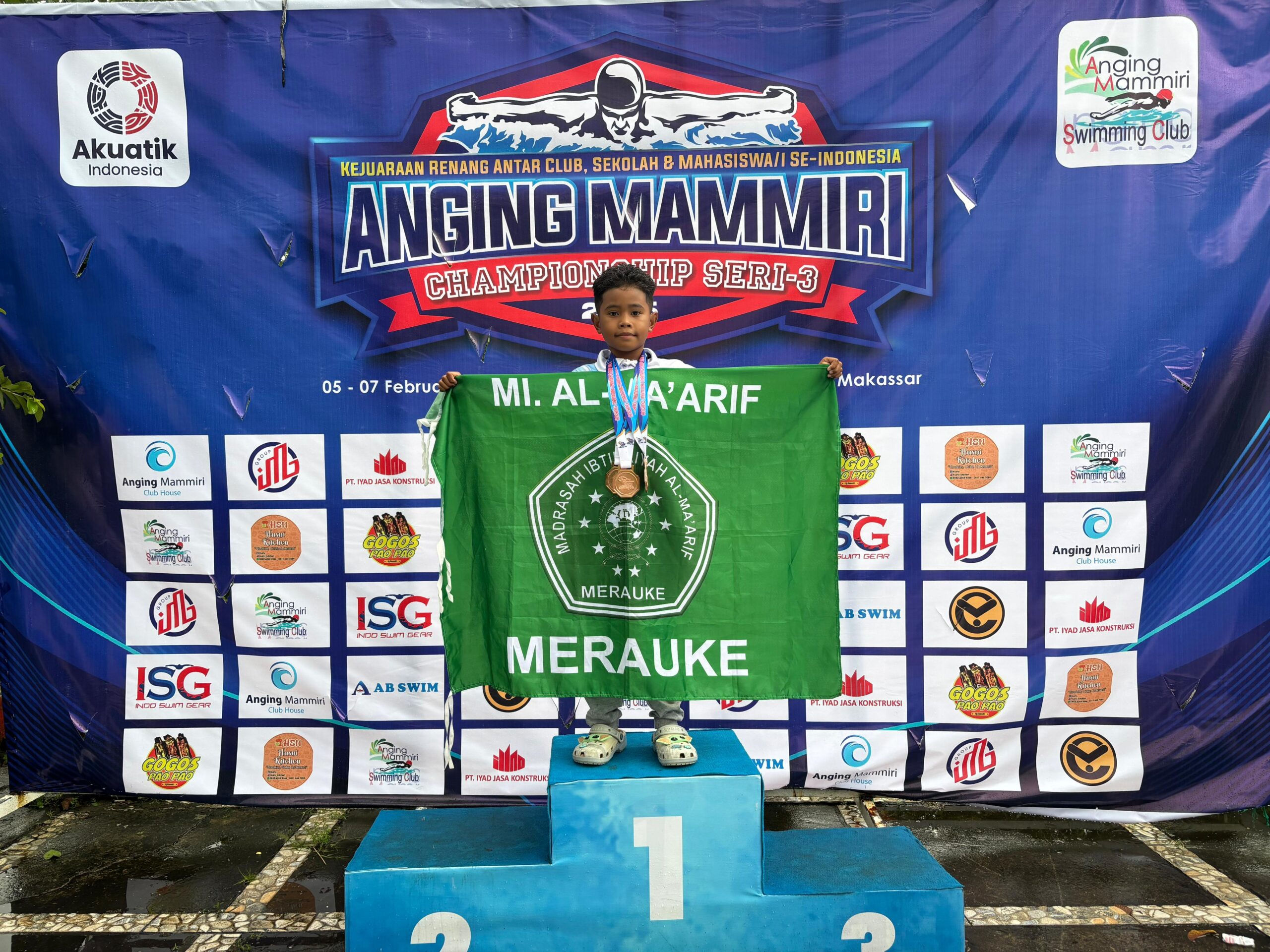 Foto: Muhammad Zaqwan Abrizam Said menunjukan bendera pataka sekolah kebanggannya MI Al Ma’arif Merauke di ajang Anging Mammiri Swimming Championship Seri-3, Makassar. Foto: Bataspapua.com/Istimewa.