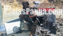 Sesosok pria yang diduga anggota KKB atau TPNPB/OPM memegang senjata api dan berpose di puing-puing pesawat diduga milik PT Associated Mission Aviation (AMA) dengan registrasi PK-RCY di Bandara Perintis Balingga, Kabupaten Yahukimo, Kamis (2/7/2026). Foto: Istimewa